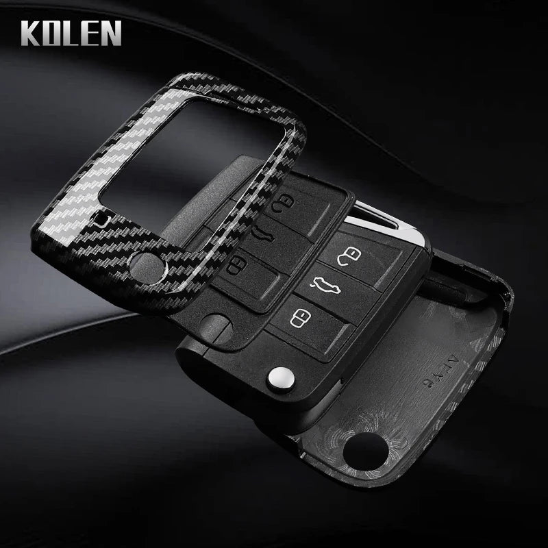 A black carbon fiber button cover for a car key, featuring a textured grip and multiple buttons.
