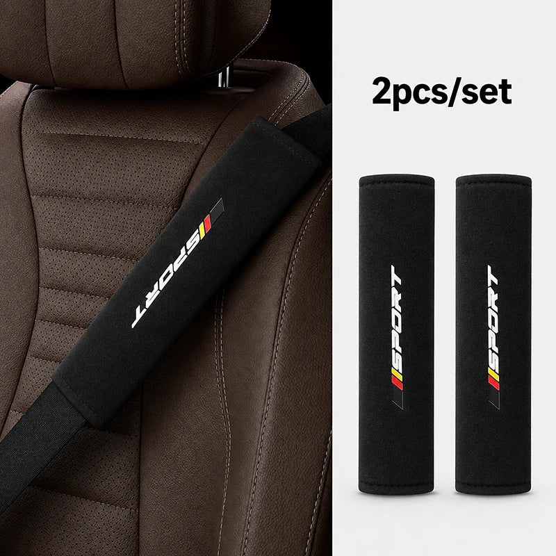 Two black sports shoulder pads for car seat belts shown against a brown leather seat.
