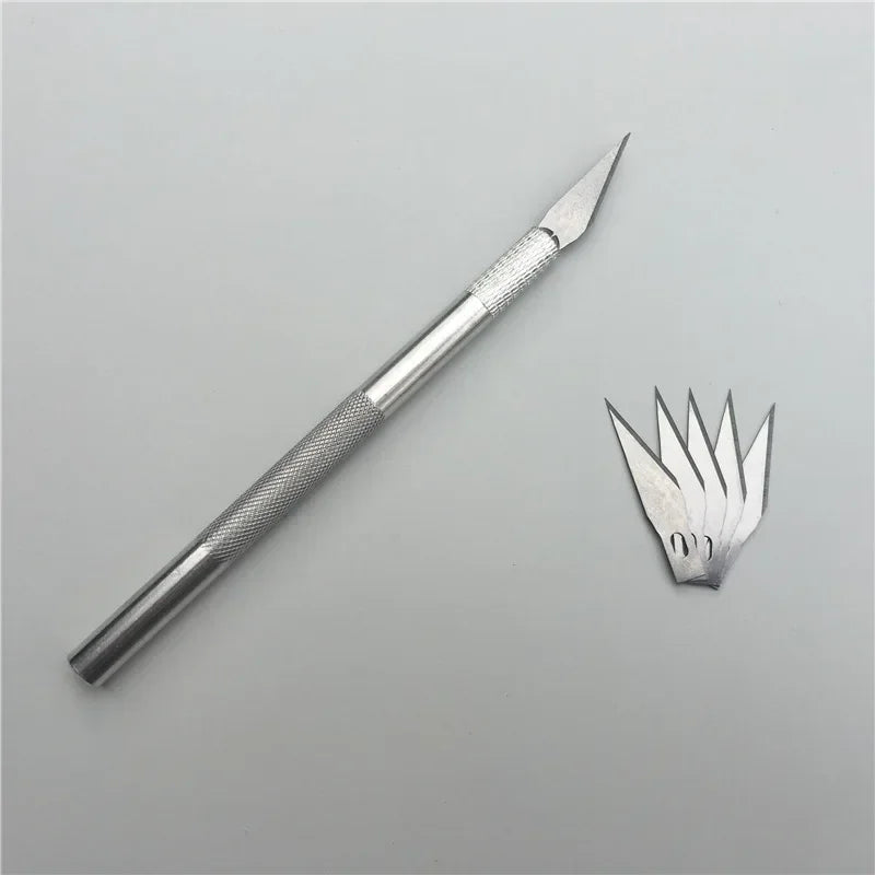 A silver vinyl wrap tool kit with a pointed blade is shown against a light gray background.