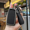 A hand holds a black zinc alloy car key case with a leather lanyard attached.