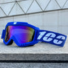 A bright blue windproof sports goggle with a white strap rests on a gray stone surface.