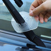 A hand is placing a clear plastic protective cover onto the wiper hole of a car windshield.