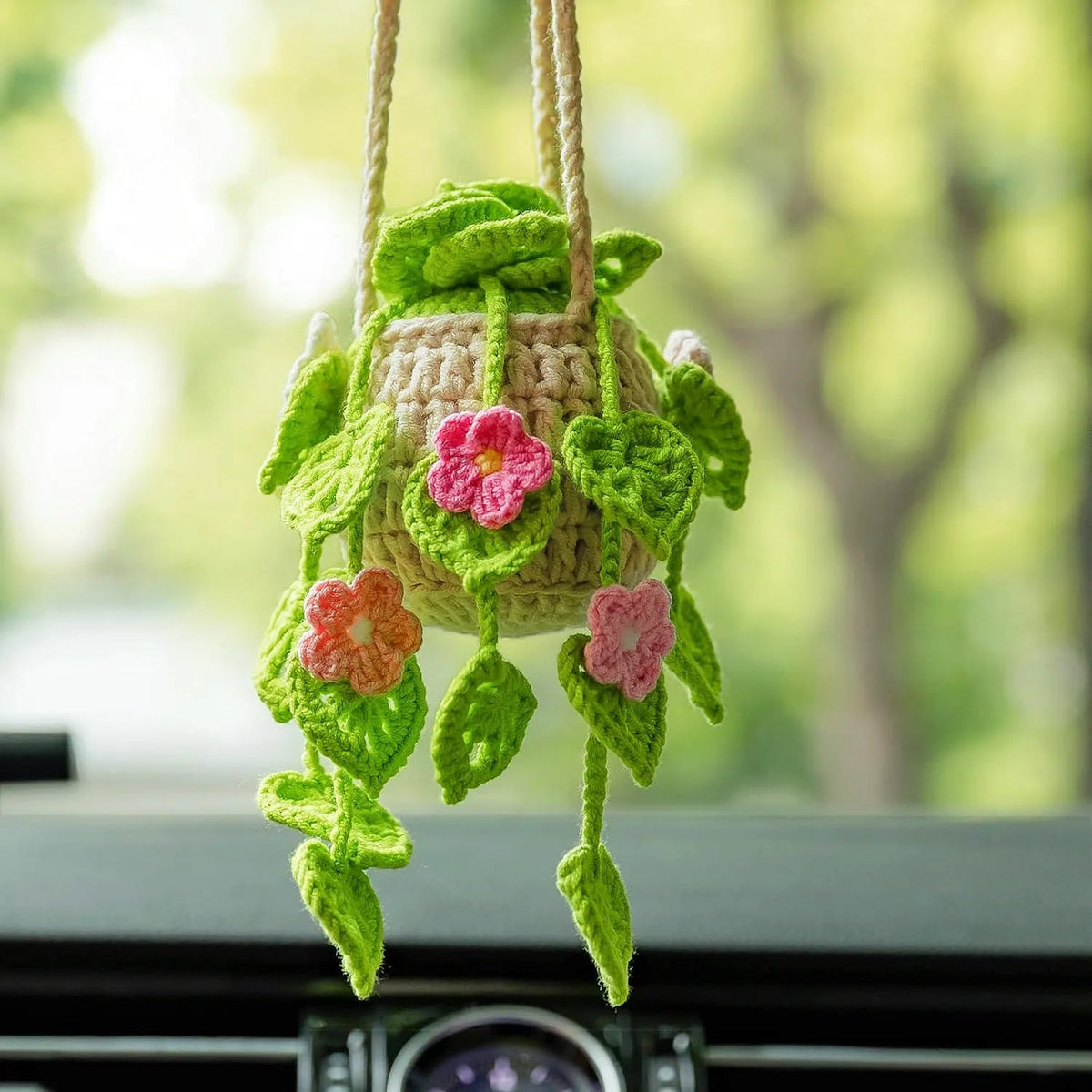 A handmade strawberry crochet hanging decor featuring pink and green flowers suspended by twine.