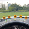 Plusieurs petits ornements de tournesol jaunes sont placés sur le tableau de bord d'une voiture.
