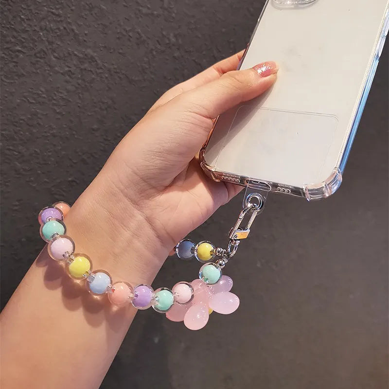 A hand holds a phone attached to a lanyard featuring round beads in pastel colors.