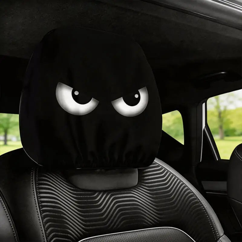 Black car headrest covers with angry eye designs placed on a black car seat.