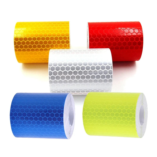 A collection of rolled high-visibility reflective tape in yellow, red, white, and blue.