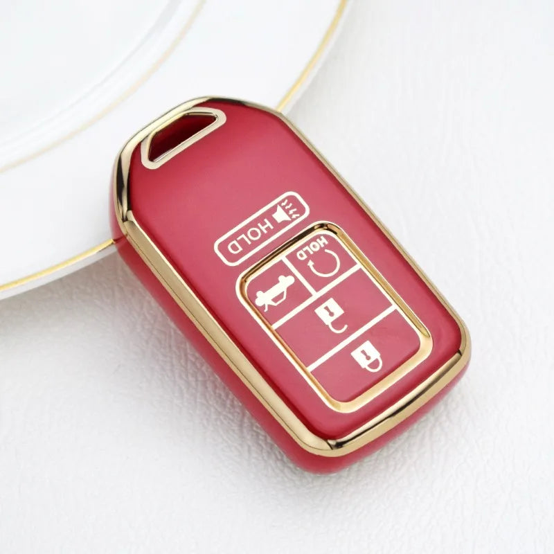 Une boîte à clés rouge avec des accents dorés posée sur une surface blanche.