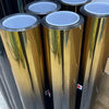 Nahaufnahme mehrerer zylindrischer Rollen von Farbverlauf-Windschutzscheibenfolie in Gold- und Silbertönen.
