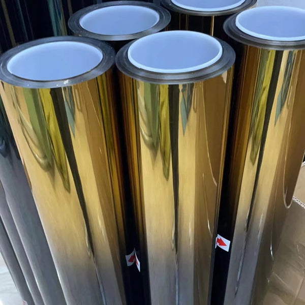 Vista cercana de varios rollos cilíndricos de película para parabrisas con degradado en tonos dorado y plateado.