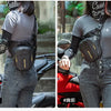 A woman wearing a gray shirt and jeans is carrying a black waterproof motorcycle fanny pack on her torso.