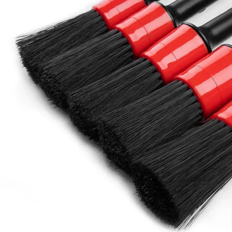 A set of professional car detailing brushes with red and black bristles shown diagonally.