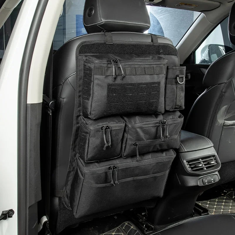 A black tactical luggage organizer bag is installed in the back seat of a car, featuring multiple compartments.