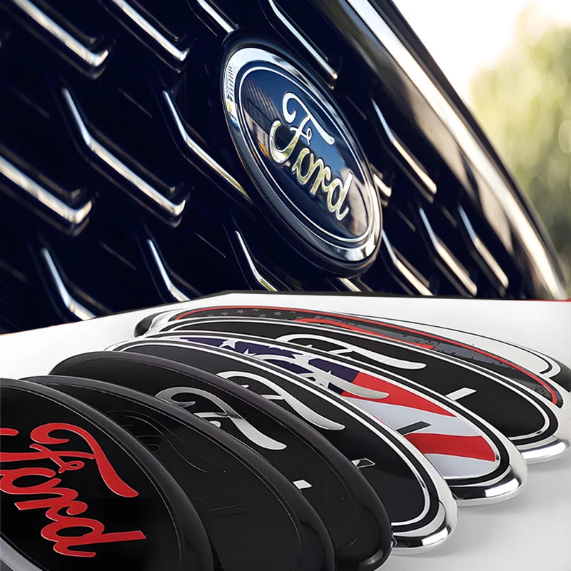 Close-up of a black car badge emblem decal for Ford models on a white surface.