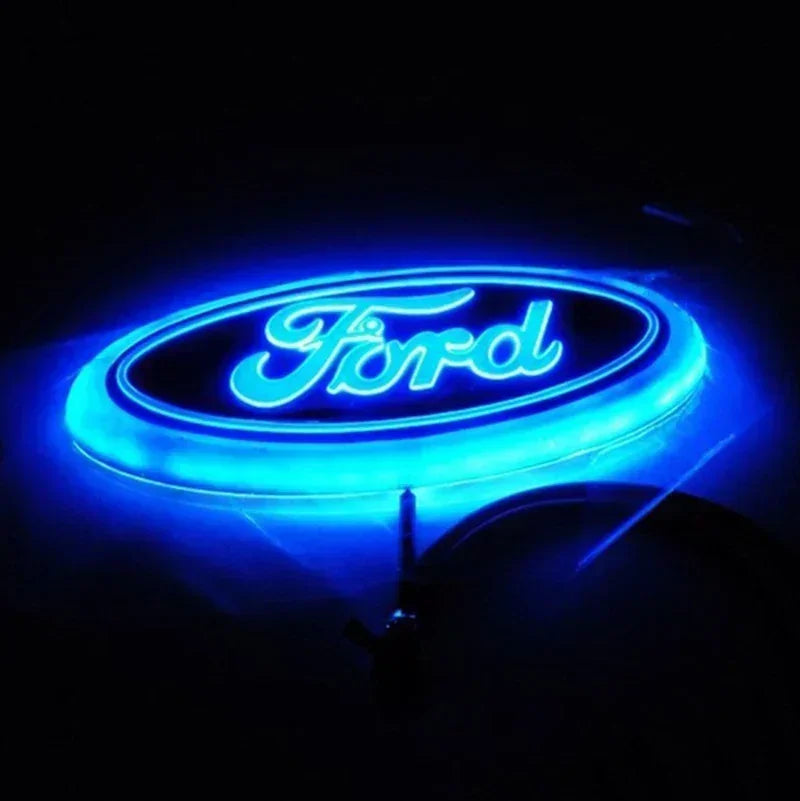Blue neon glow of a Ford logo emblem against a dark background.