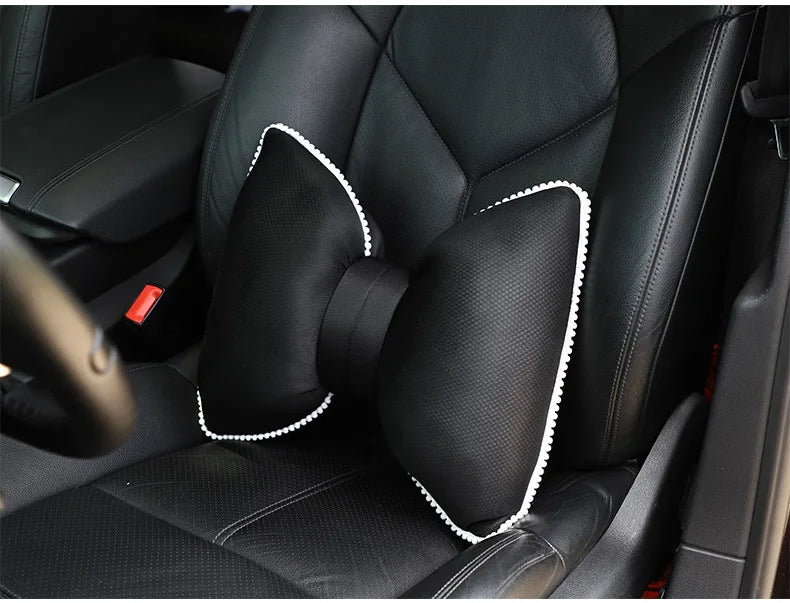 Black ergonomic car headrest pillow with a bow design shown inside a car seat.