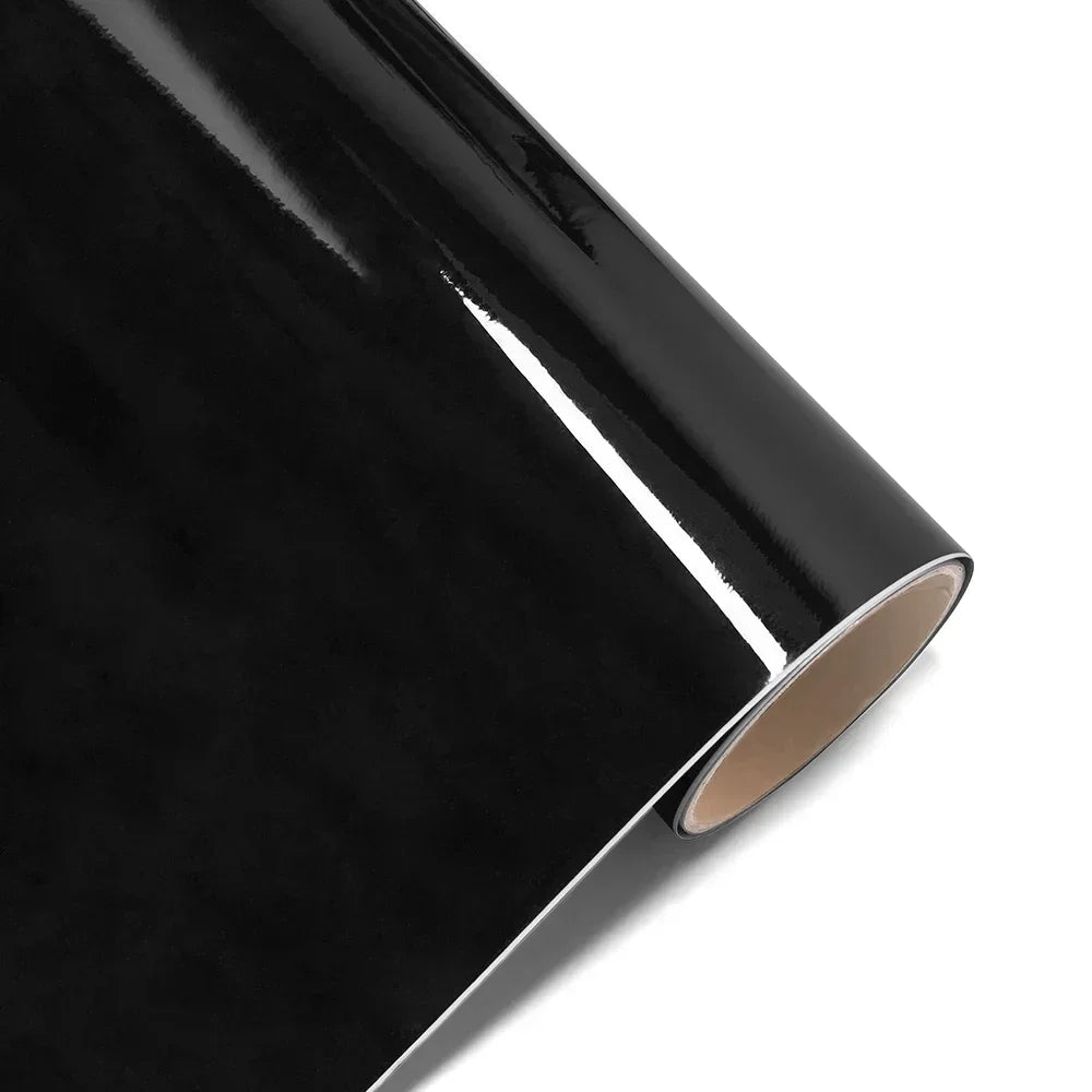 Close-up view of glossy black car wrap film showing a smooth, reflective surface and an edge.