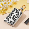 A leopard print car key holder with a gold clasp resting on a light pink surface.