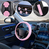 A car interior showing a pink steering wheel cover and various comfort pads installed on the dashboard.