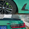 Close-up of a green BMW with black wheels and tri-color decals on the rear body panel.