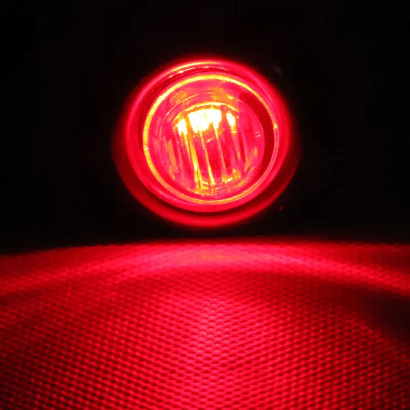 Close-up view of a bright red vehicle marker light illuminating a textured surface.
