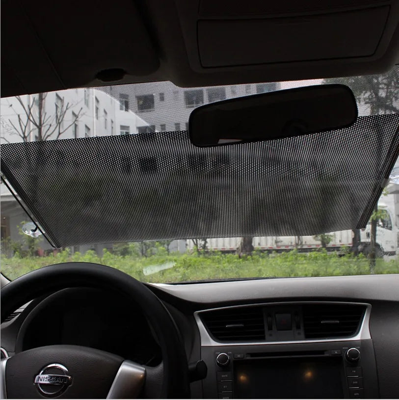 Interior view of a car showing a retractable windshield sun shade installed on the glass.