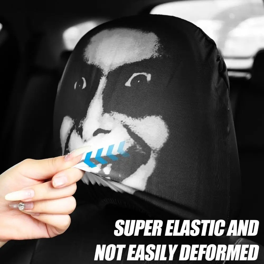 A hand is holding a black car seat headrest cover featuring a white face design with blue stripes.