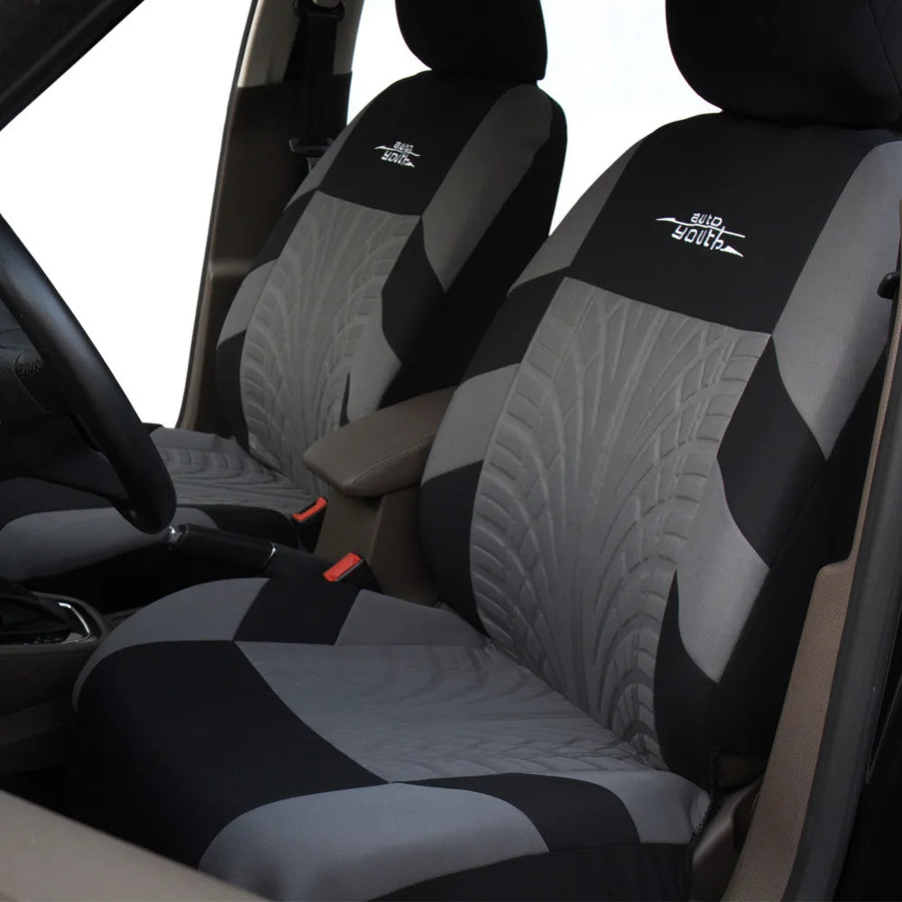 Close-up view of a black and gray car seat with supportive fabric covers installed on the seat cushion.