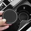 A hand holds a black decorative rhinestone coaster, showing its textured surface and sparkling rim.
