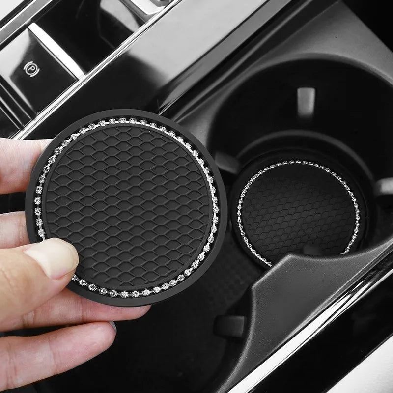 A hand holds a black decorative rhinestone coaster, showing its textured surface and sparkling rim.