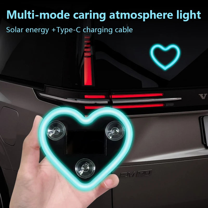 Une main tient une décoration lumineuse en forme de cœur au néon dans l'habitacle d'une voiture, alimentée par énergie solair