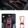 Interior view of a Jeep Wrangler gear shift panel with red trim stickers and cup holders.