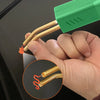 A hand holds a green plastic welding repair kit with staples for car bumpers, showing the metal rods inside.