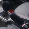 Gant de voiture d'hiver en peluche noire sur un siège de voiture sombre.