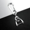 Silver metal key fob holder with a split ring and loop design resting on a black surface.