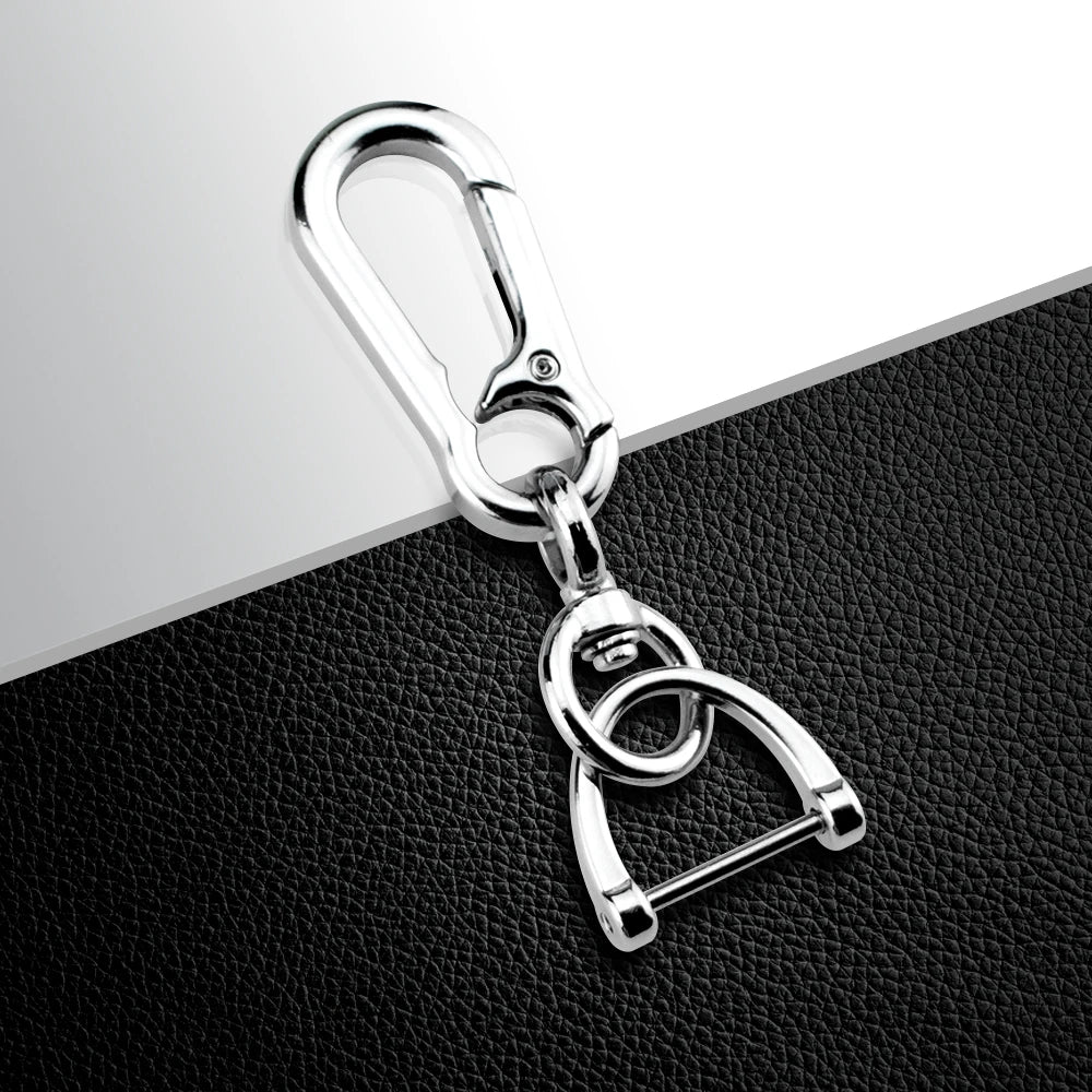 Silver metal key fob holder with a split ring and loop design resting on a black surface.