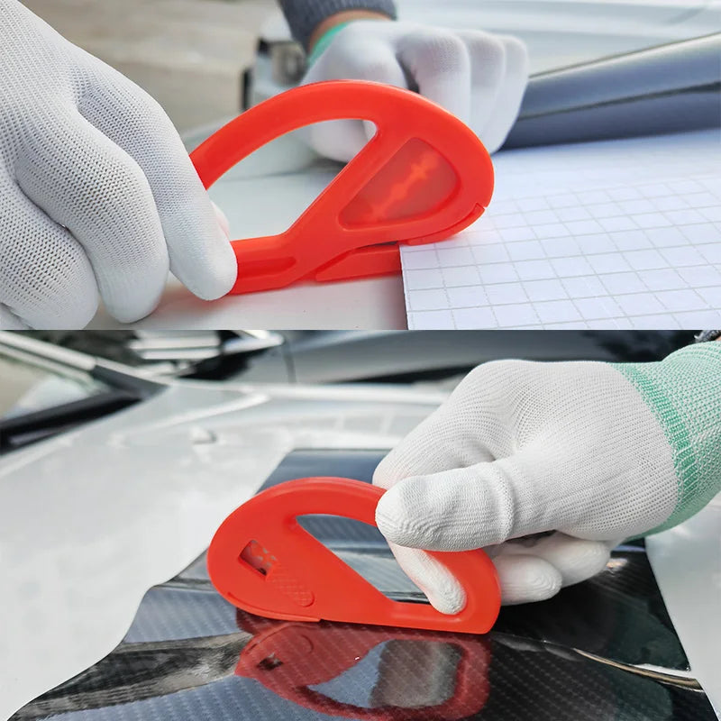 A hand wearing a white glove is using an orange professional car vinyl wrapping tool on a car surface.