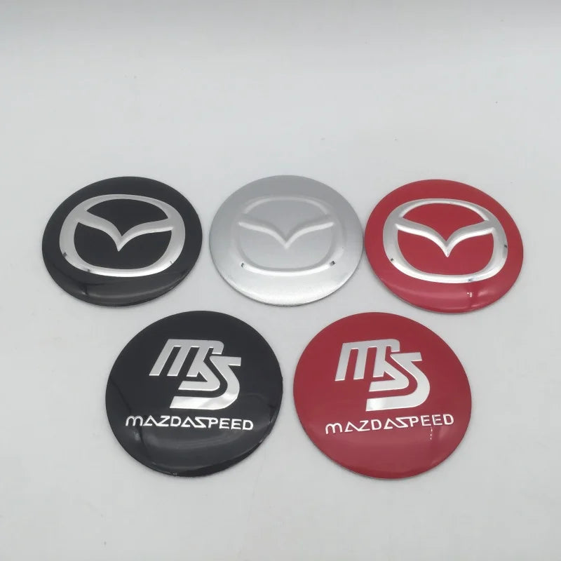 Four circular center caps or decals featuring the MazdaSpeed logo in silver and red colors.