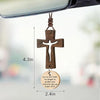 A wooden cross ornament with a hanging tag and engraved text for protection.