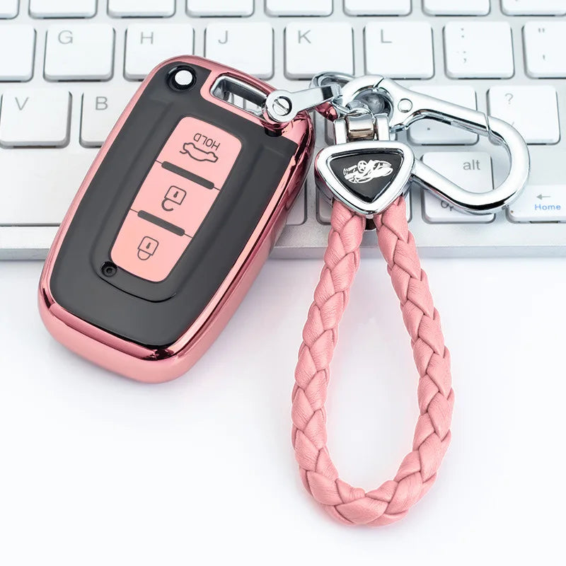 A pink metallic car key case with a braided cord attached, resting on a white keyboard.