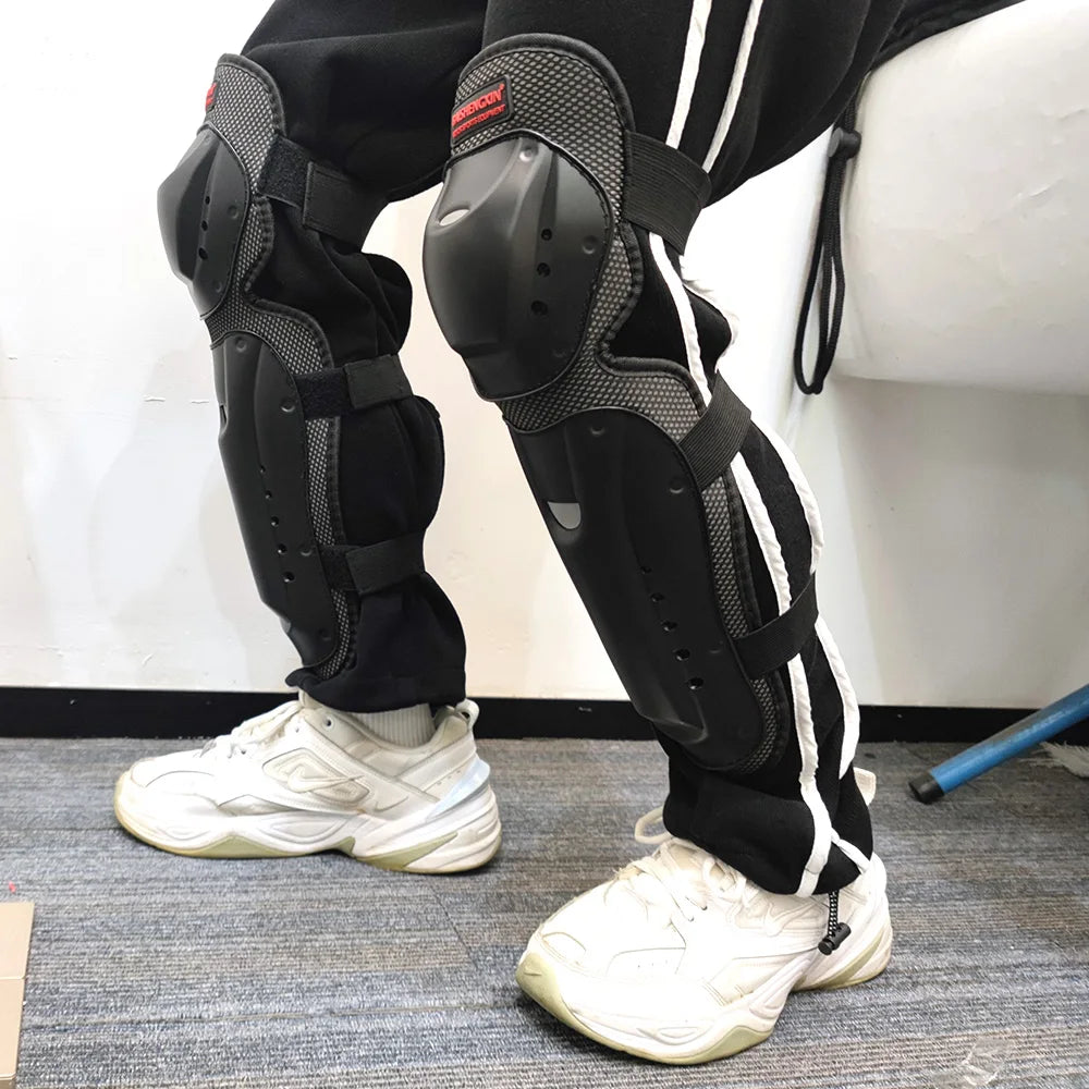 A person wearing black motorcycle protection pads on their legs and white sneakers.