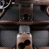 Interior view of a car showing dark brown quilted floor mats and leather trim.