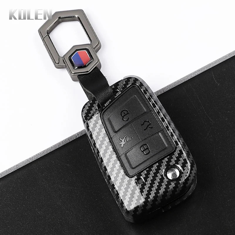 A black carbon fiber button cover for a car key, featuring a silver clasp and a red and blue accent.