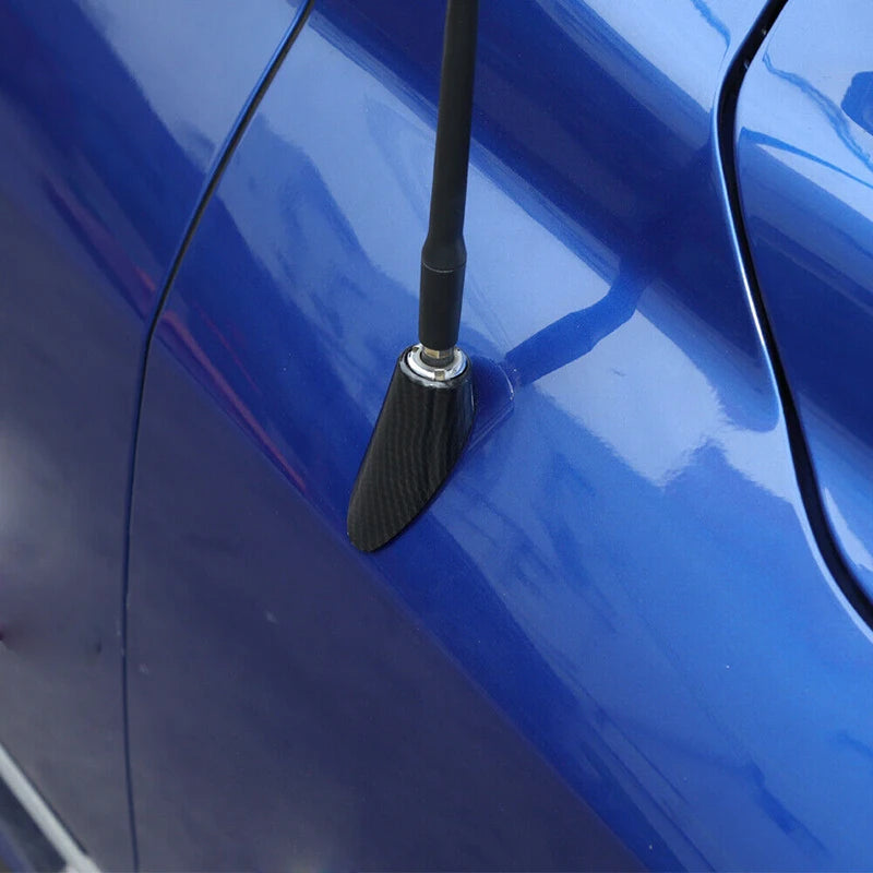 Close-up of a black carbon fiber look antenna base trim mounted on a blue vehicle body panel.