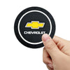 A hand holds a black car anti-slip coaster with a yellow Chevrolet emblem and text.