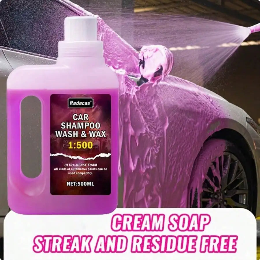 A bottle of pink car shampoo and wax is shown spraying foam onto a car's paint surface.