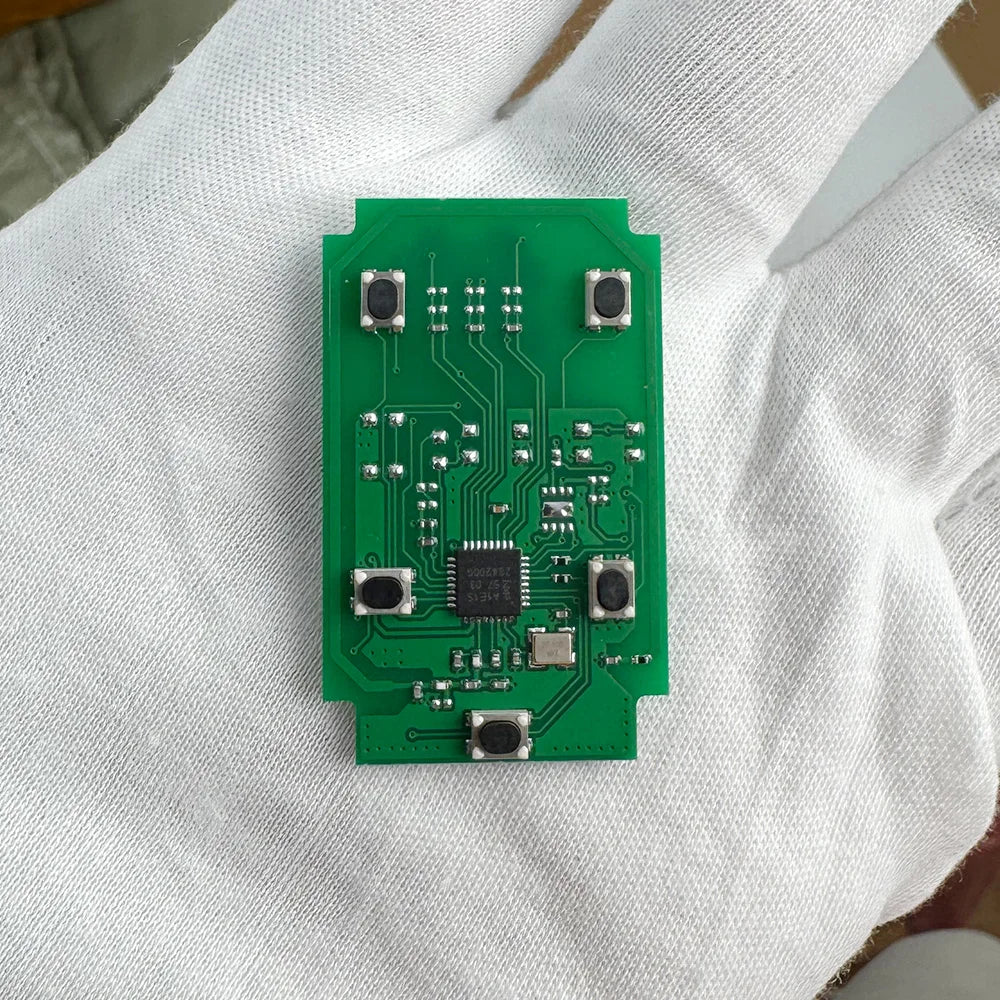 A green electronic circuit board with various components is held in a person's hand.