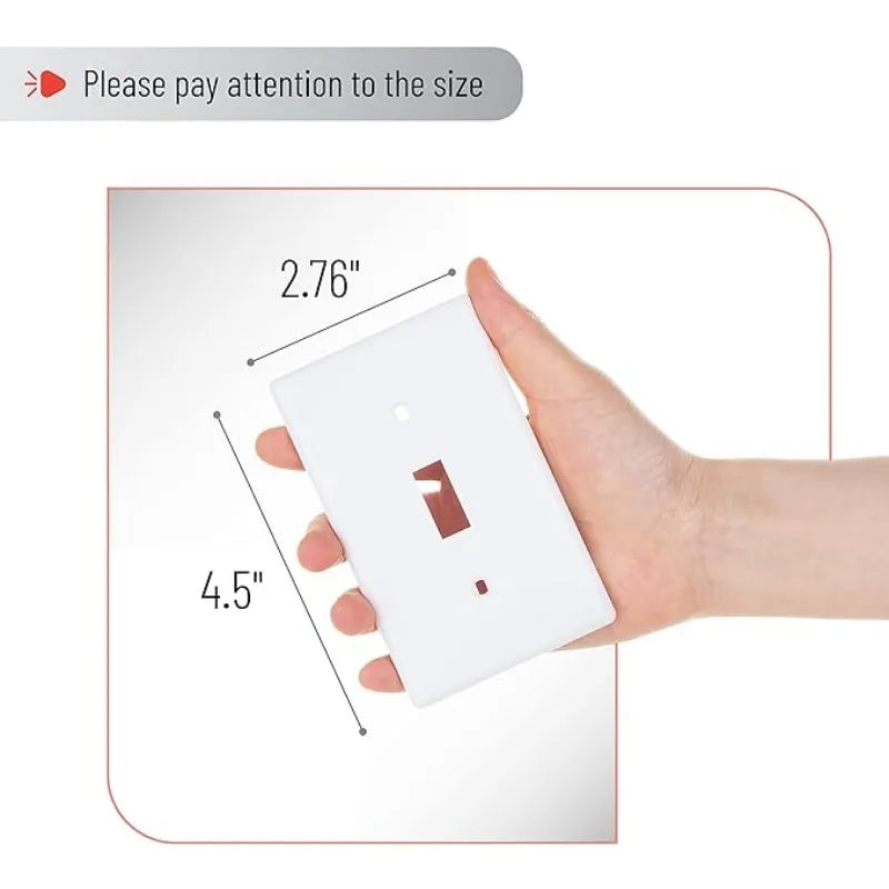 A hand holds a white electrical light switch cover plate, showing its size with a ruler.