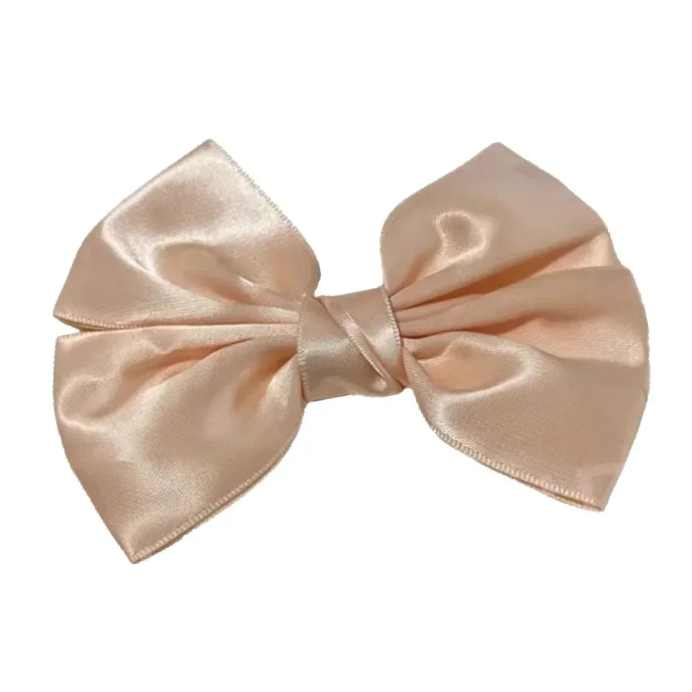 A light pink satin silk hair bow tied in a classic bow shape.