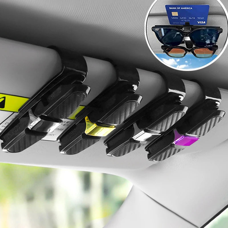 A black clip designed to hold sunglasses and eyeglasses is shown mounted on a car interior surface.